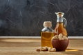 Aromatic oil in a glass jar and bottle with peanuts in bowl on wooden table, close-up. Royalty Free Stock Photo