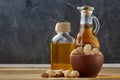 Aromatic oil in a glass jar and bottle with peanuts in bowl on wooden table, close-up Royalty Free Stock Photo