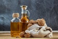 Aromatic oil in a glass jar and bottle with peanuts in bowl on wooden table, close-up, vertical Royalty Free Stock Photo