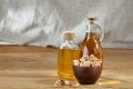 Aromatic oil in a glass jar and bottle with pistacios in bowl on wooden table, close-up.