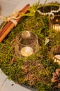 Aromatic sinnamon rolls tied together with ribbon. Platter with moss, cinnamon sticks, cone and candles in glass cups