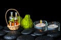 Aromatic spa concept of bergamot fruits, candles and bottles essential oil in basket on zen black stones with dew, closeup Royalty Free Stock Photo