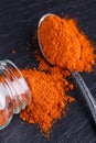 Aromatic spicy chilli powder on a dark stone background