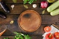 Around the round kitchen board different vegetables, top view