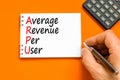 ARPU average revenue per user symbol. Concept words ARPU average revenue per user on white note on beautiful orange background.