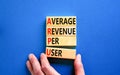 ARPU average revenue per user symbol. Concept words ARPU average revenue per user on wooden block on beautiful blue background.