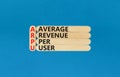 ARPU average revenue per user symbol. Concept words ARPU average revenue per user on wooden stick on beautiful blue background.