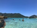 Arraial do Cabo, Rio de Janeiro, Brazil, January 1, 2019: Bathers in and out of the water watching a small vessel approach in a