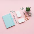 Arranged on a pink background are a light blue notebook, silver pen, small stack of w Royalty Free Stock Photo