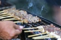 Arranged pork skewers grilled on a hot stove. smoke floating above There is a blurry hand foreground. Selective focus. It is a Royalty Free Stock Photo