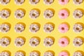 Arranged small ring donuts with white and pinl glaze. Colorful crumbs on a yellow pastel background. Pattern. Flat lay Royalty Free Stock Photo