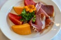 Arrangement of Delicatessen Cold Cuts with charcuterie, melon and watermelon decorated with orange flower and parsley. Soft focus