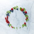An Arrangement of fresh raspberries, blueberries, red currant and mint leaves on gray marble background. Royalty Free Stock Photo