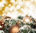 An arrangement of golden Christmas baubles against a festive bokeh of twinkling gold lights with copyspace Royalty Free Stock Photo