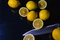 Arrangement of half lemons and whole organic lemons with a knife blade on a glittery black glass background Royalty Free Stock Photo