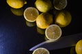 Arrangement of half lemons and whole organic lemons with a knife blade on a glittery black glass background Royalty Free Stock Photo