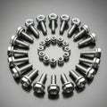 Arrangement of metallic bolts and nuts on a reflective gray surface. Larger bolts with Royalty Free Stock Photo