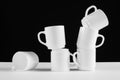 Arrangement of six white mugs with a handle. Black background