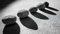 Arrangement of stones casting shadows on a surface during daylight hours in a monochrome setting Royalty Free Stock Photo