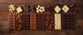 An array of assorted chocolate bars, including white, milk, and dark chocolate, accompanied by nuts on a dark surface Royalty Free Stock Photo