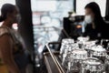 An Array of Clean Glasses in a Coffee Shop with a Cashier Serving a Female Customer on the Background Royalty Free Stock Photo