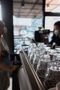 An Array of Clean Glasses in a Coffee Shop with a Cashier Serving a Female Customer on the Background Royalty Free Stock Photo