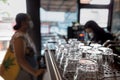 An Array of Clean Glasses in a Coffee Shop with a Cashier Serving a Female Customer on the Background Royalty Free Stock Photo