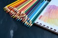 array of colored pencils fanned out beside a sketch pad Royalty Free Stock Photo