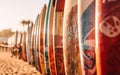 Array of colorful surfboards lined up on the beach sand on a sunny day