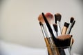 Array of cosmetic makeup brushes arranged in a cup on a wooden tabletop, ready for use Royalty Free Stock Photo