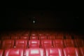 Array of red-illuminated cinema chairs in a dark room, illuminated by a warm soft light. Royalty Free Stock Photo