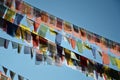 Array of vibrantly colored prayer flags fluttering in the wind against a clear, bright blue sky. Royalty Free Stock Photo