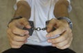 Arrested computer hacker and cyber criminal with handcuffs, close up of hands