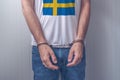 Arrested man with cuffed hands wearing shirt with Swedish flag