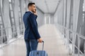 After Arrival. Smiling Arab Businessman Talking On Cellphone While Passing Airport Gate Royalty Free Stock Photo