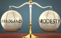 Arrogance and modesty staying in balance - pictured as a metal scale with weights and labels arrogance and modesty to symbolize