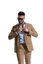 Arrogant businessman in brown suit with sunglasses opening shirt