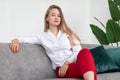 Arrogant confident young woman sitting on couch and looking down at camera. Concept of businesswoman