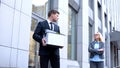 Arrogant female director looking male employee with stuff box, work competition Royalty Free Stock Photo