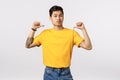 Arrogant and self-assured, stylish asian macho man in yellow t-shirt, thinking he is awesome sexy and cool, pointing