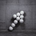 Arrow of spheres in front of a gray wall