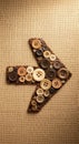 Arrow composed of various-sized buttons in shades of brown and beige, arranged on a textured burlap Royalty Free Stock Photo