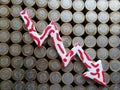 arrow down formed with plasticine in red and white and stacked coins of mexican pesos