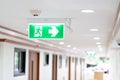 A Arrow light box sign of EMERGENCY FIRE EXIT is hung on the ceiling in hospital walkway, Idea for event fire or evacuation drills