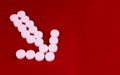 Arrow made of white pills on a red background. Copy space.