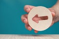 Arrow pointing left on a blue background. Banner with an arrow in a wooden circle in a hand close-up points to the left Royalty Free Stock Photo