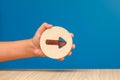 Arrow pointing right on a blue background. Banner with an arrow in a wooden circle in a hand close-up pointing to the Royalty Free Stock Photo