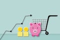 Arrow rising up with pink piggy bank, coins and shopping cart as metaphor rising cost of living. inflation financial crisis. Royalty Free Stock Photo