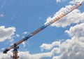 An arrow of a tower crane against a blue sky, divides the image diagonally