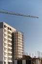 Arrow of a tower crane over the construction of a multi-storey building against the background of the sky. Builders work
